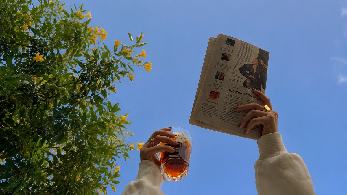 Person reading a newspaper outdoors under open sky, representing independence and self-directed action